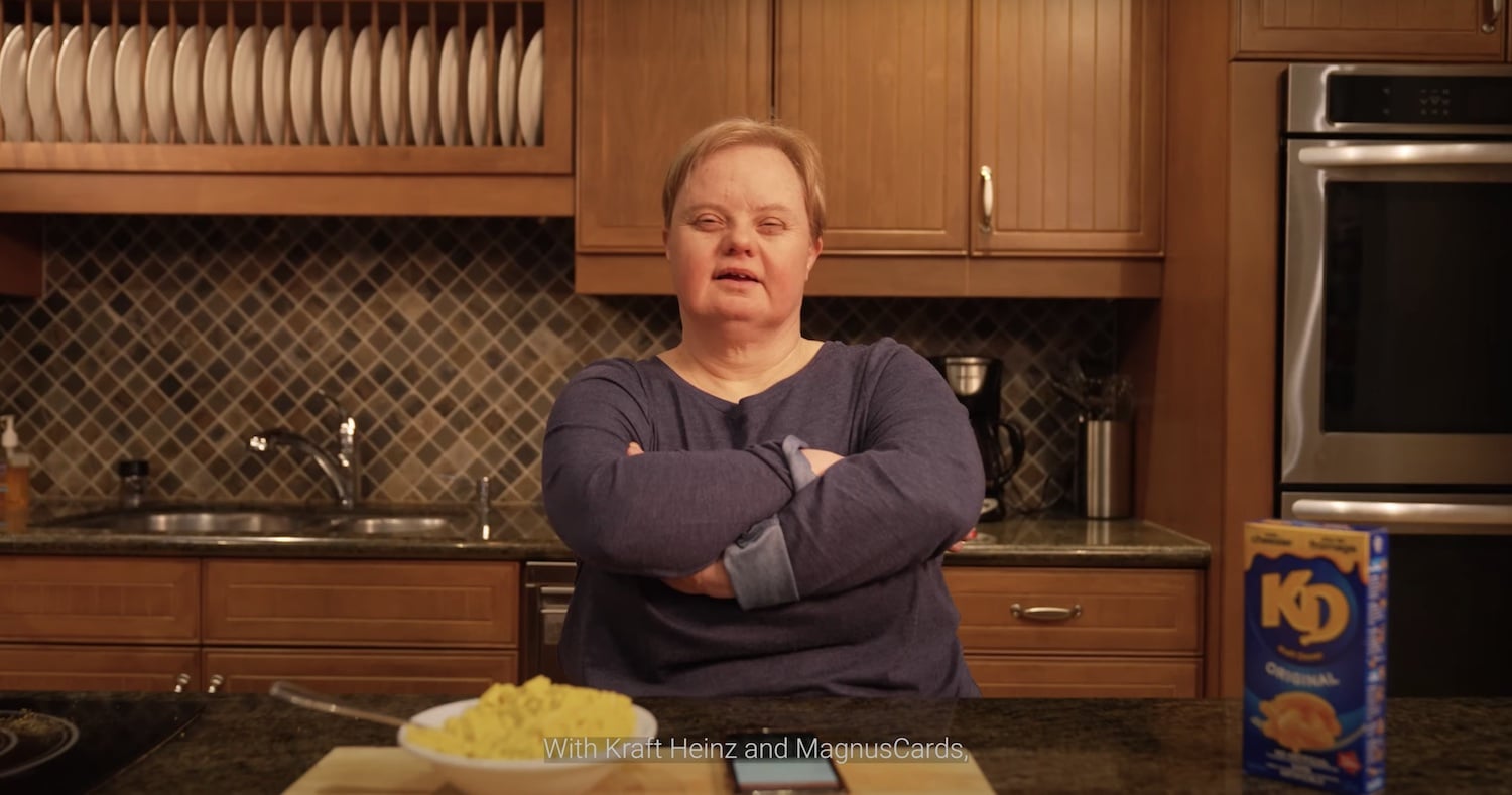 Woman smiles confidently in her kitchen after cooking Kraft dinner with support from the MagnusCards app